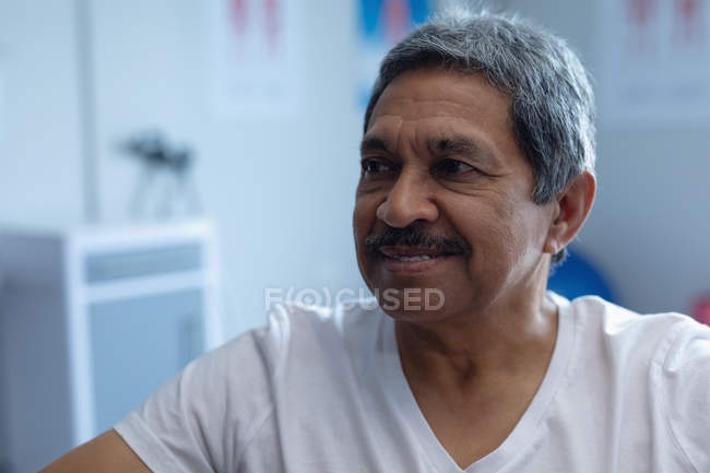 Front view of happy mixed race male patient looking away in hospital — Stock Photo