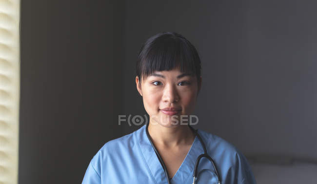 Retrato de la hermosa mujer asiática feliz médico de pie con estetoscopio alrededor del cuello en el hospital - foto de stock