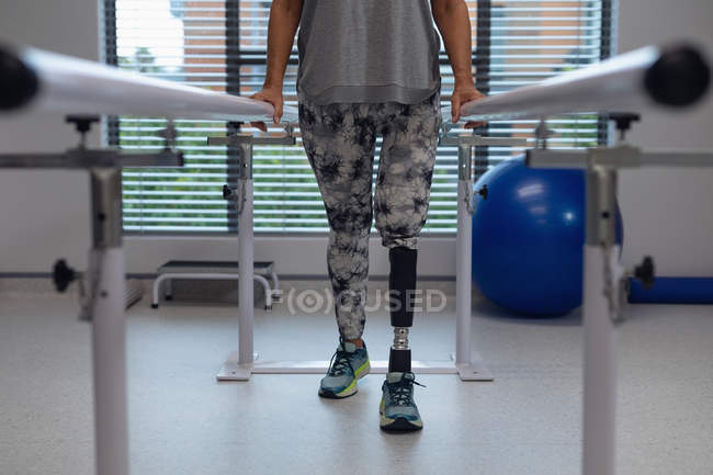 Faible section de patiente amputée marchant avec des barres parallèles à l'hôpital — Photo de stock