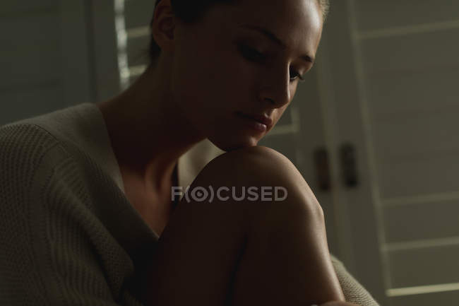 Close-up of thoughtful Caucasian woman sitting on window seat at home — Stock Photo