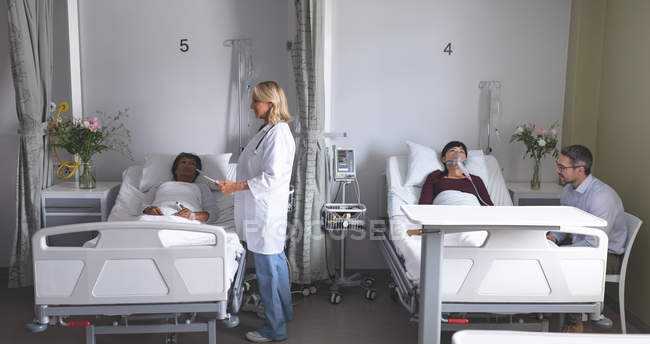 Frontansicht verschiedener Ärzte, die mit Patienten auf der Station im Krankenhaus interagieren — Stockfoto