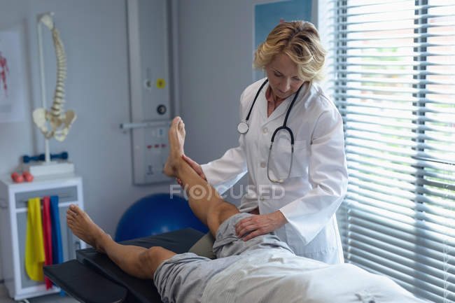 Вид на зрілий жіночий лікар вивчення чоловічого пацієнта назад в лікарню — стокове фото