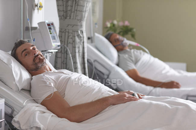 Porträt eines kaukasischen männlichen Patienten, der sich auf der Krankenstation im Bett entspannt — Stockfoto