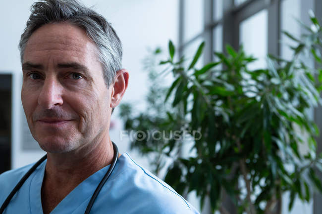Портрет симпатичного взрослого белого врача, смотрящего на камеру в коридоре больницы — стоковое фото
