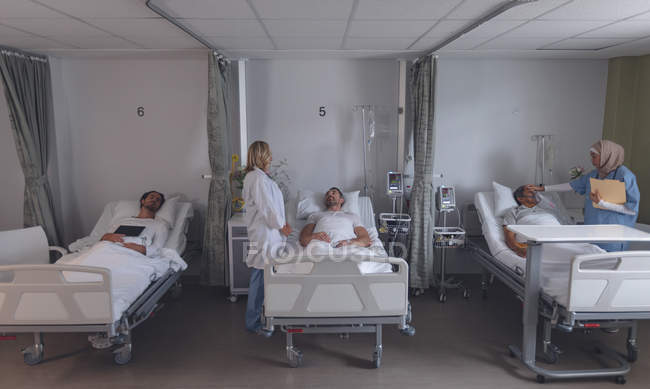 Panoramica dei diversi medici di sesso femminile che interagiscono con pazienti di sesso maschile nel reparto ospedaliero — Foto stock