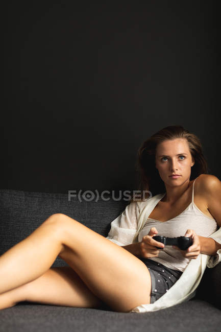 Front view of beautiful Caucasian woman playing video game in living room at home — Stock Photo