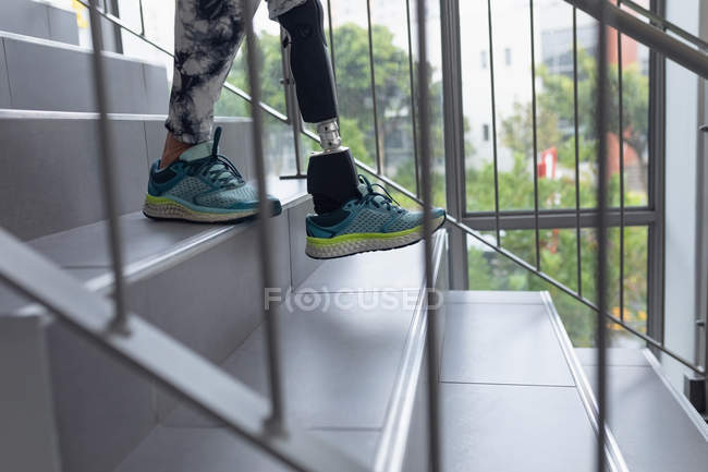 Нижняя часть пациентки с ограниченными возможностями с протезной ногой, идущей по лестнице в больнице — стоковое фото