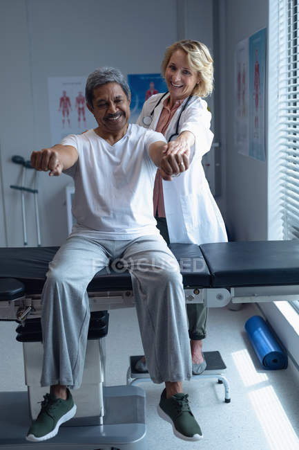 Vorderansicht einer kaukasischen Ärztin, die einen älteren Mischlingskranken im Krankenhaus untersucht — Stockfoto