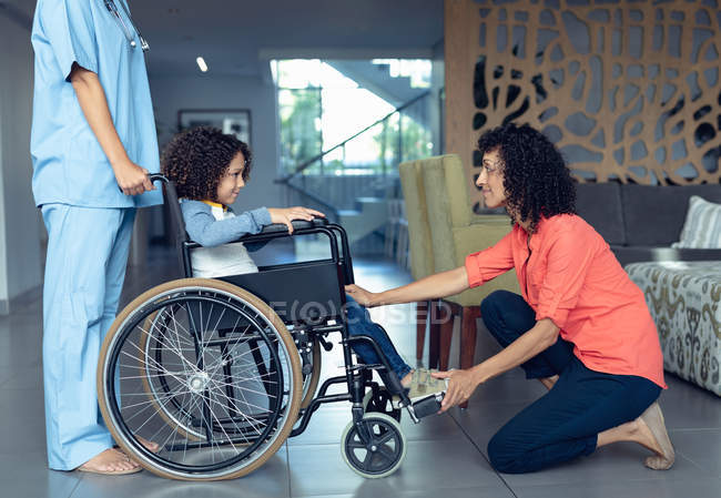 Side view of mixed-race mother consoling her disabled son in the lobby at hospital. — Stock Photo