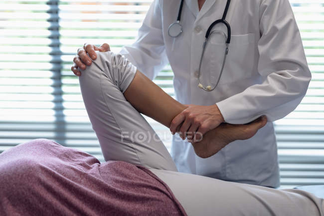 Secção intermédia do médico feminino que examina os doentes perna no hospital — Fotografia de Stock