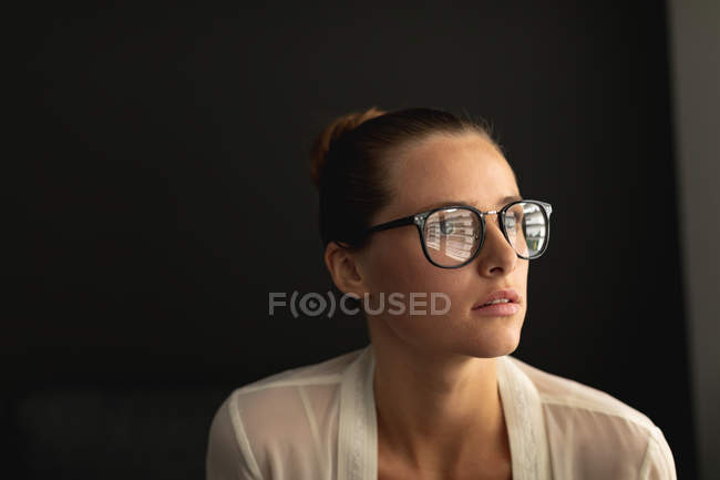 Vista lateral da mulher caucasiana pensativa olhando para longe enquanto sentada em um sofá na sala de estar em casa — Fotografia de Stock