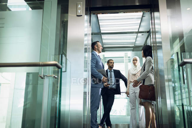 Visão de baixo ângulo de diversos empresários usando elevador no escritório moderno — Fotografia de Stock