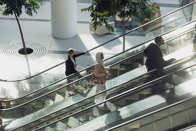 Aerial view of diverse business people using escalators in modern office — Stock Photo