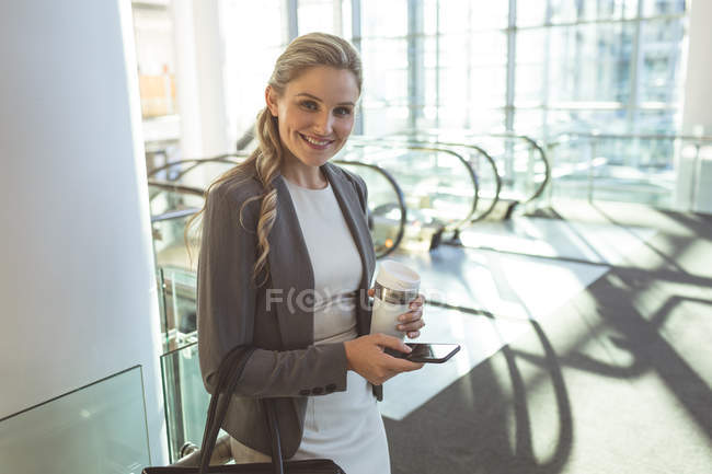 Вид збоку щасливої бізнес-леді, дивлячись на камеру в сучасному офісному будинку — стокове фото