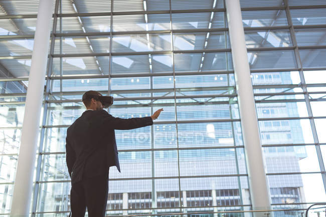 Vue à faible angle de l'homme d'affaires en utilisant un casque de réalité virtuelle dans un immeuble de bureaux moderne — Photo de stock
