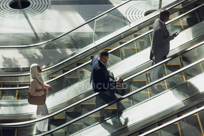 Veduta aerea di diversi uomini d'affari che utilizzano scale mobili in ufficio moderno — Foto stock