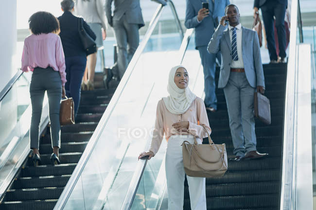 Front view of diverse business people using escalators in modern office — Stock Photo