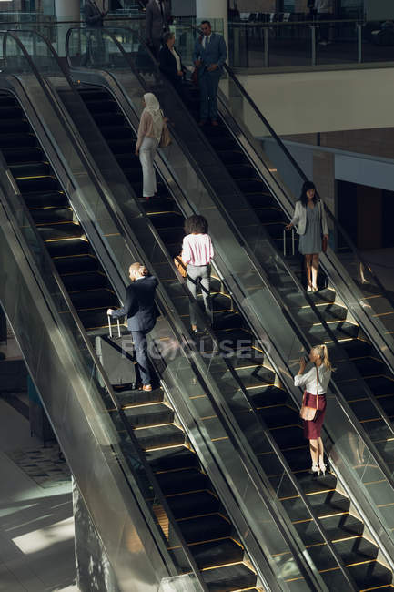 Aerial view of diverse business people using escalators in modern office — Stock Photo