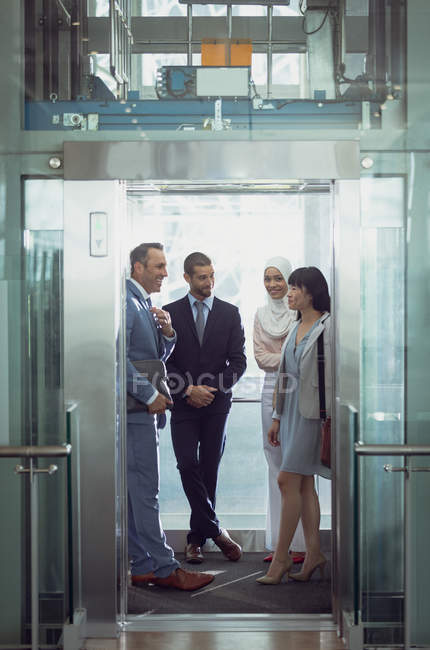 Vue de face de divers hommes d'affaires utilisant un ascenseur dans un bureau moderne — Photo de stock