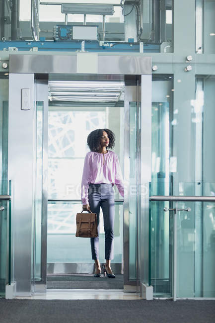 Vista frontal de la ejecutiva afroamericana tomando el ascensor en la oficina moderna - foto de stock