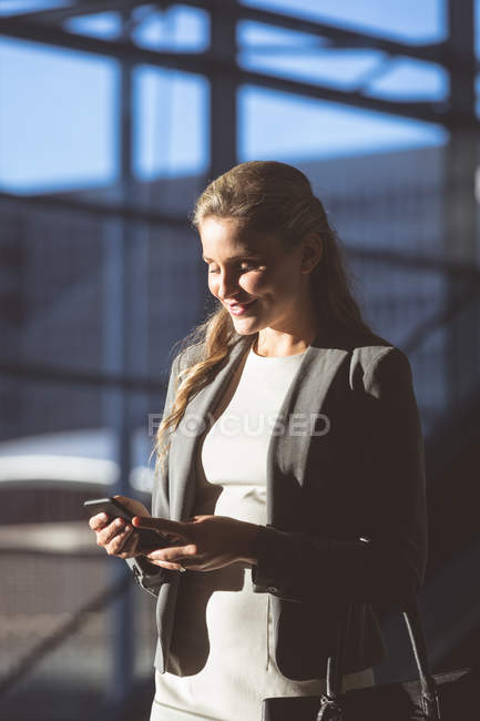 Крупним планом бізнес-леді, використовуючи мобільний телефон у вестибюлі в сучасному офісному будинку — стокове фото