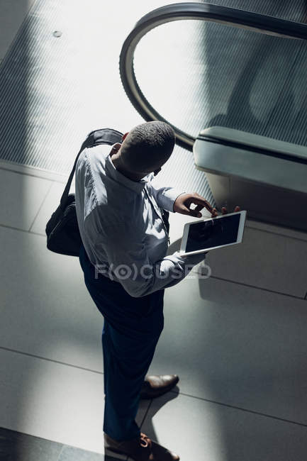 Vista de alto ángulo del hombre de negocios afroamericano mirando tableta digital en la oficina moderna - foto de stock
