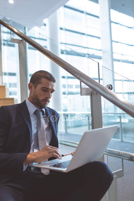 Close-up de homem de negócios trabalhando em laptop em escadas em um prédio de escritórios moderno — Fotografia de Stock