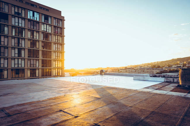 Ein Swimmingpool auf dem Dach mit Blick auf ein Gebäude und den Sonnenuntergang — Stockfoto