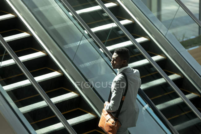 Vista lateral del hombre de negocios afroamericano de pie en ascensor en la oficina moderna - foto de stock