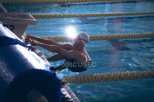 Side view of a male Caucasian swimmer holding on to the sides of the swimming pool — Stock Photo