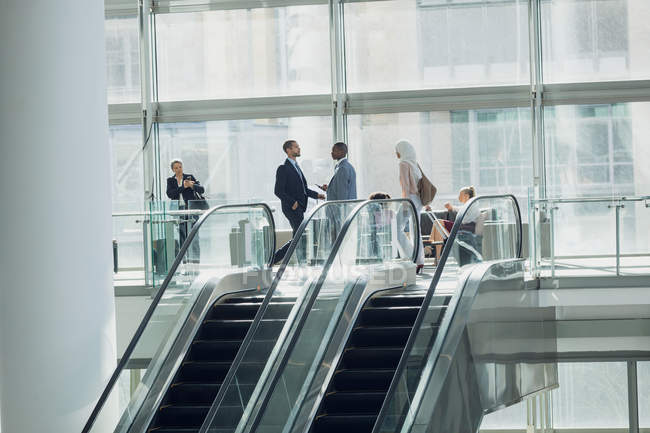 Vista lateral de gente de negocios diversa caminando en la oficina moderna - foto de stock