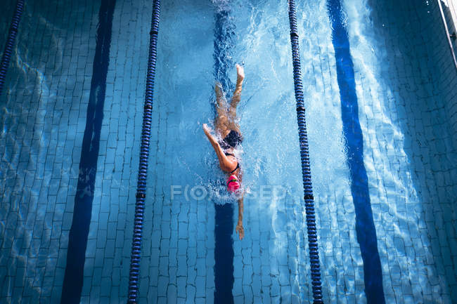 Hochwinkelaufnahme einer kaukasischen Frau mit pinkfarbener Badekappe und Brille bei einem Freestyle-Schlaganfall in einem Schwimmbad — Stockfoto