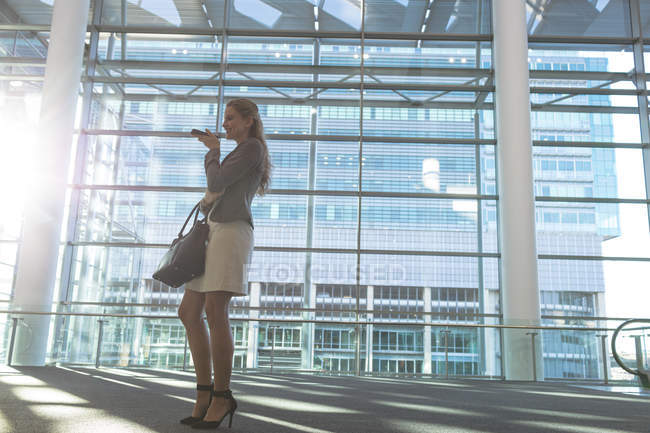 Низький кут зору бізнес-леді розмовляє на мобільному телефоні в сучасному офісному будинку — стокове фото
