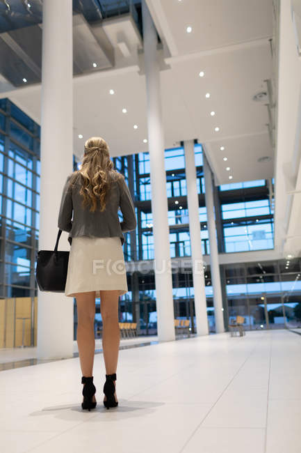 Rückansicht einer Geschäftsfrau, die in der Lobby eines modernen Büros steht — Stockfoto