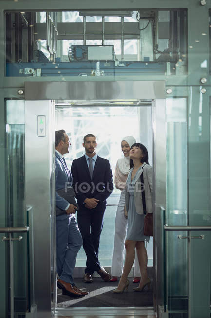 Вид спереди различных бизнесменов, пользующихся лифтом в современном офисе — стоковое фото
