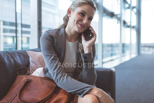 Gros plan d'une femme d'affaires parlant sur son téléphone portable dans le hall d'entrée d'un bureau moderne — Photo de stock