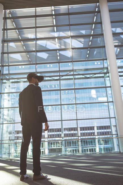 Low angle view of businessman using virtual reality headset in a modern office building — Stock Photo