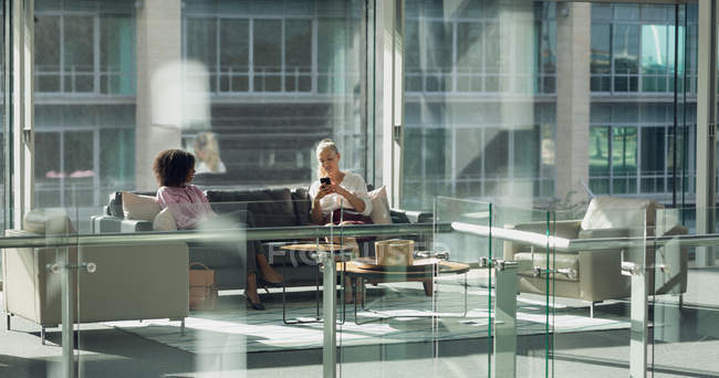 Вид спереду на різноманітних бізнесменів, що сидять на дивані в сучасному офісі — стокове фото