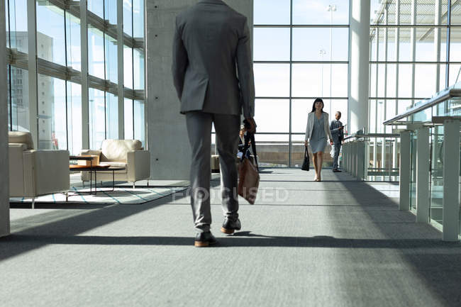 Rear view of businessman walking down the hallway in modern office — Stock Photo