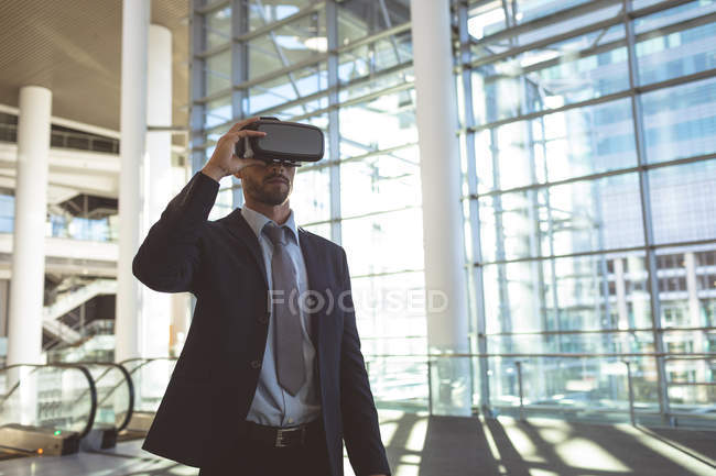 Вид спереду бізнесмена з використанням гарнітури віртуальної реальності в сучасній офісній будівлі — стокове фото