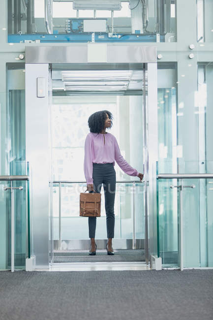 Vista frontale dell'esecutivo afroamericano femminile che prende l'ascensore in un ufficio moderno — Foto stock