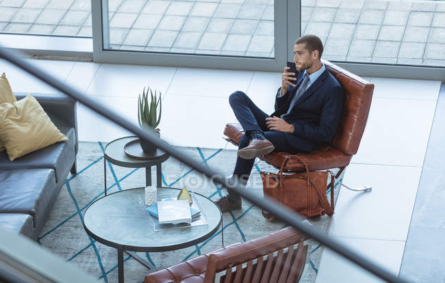 Високий кут зору бізнесмена, що розмовляє на мобільному телефоні у вестибюлі в сучасному офісі — стокове фото