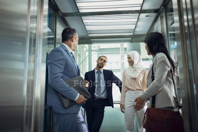 Niedrige Blickwinkel auf diverse Geschäftsleute, die Aufzüge in modernen Büros nutzen — Stockfoto
