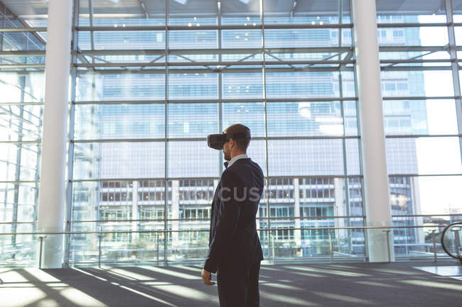 Side view of businessman using virtual reality headset in a modern office building — Stock Photo