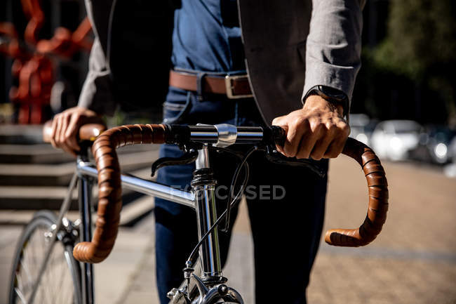 Vue de face au milieu d'un homme marchant et roulant son vélo dans la ville. Nomade numérique en mouvement . — Photo de stock