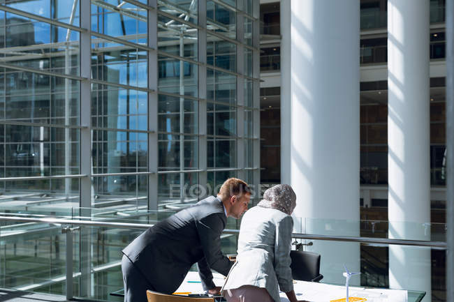 Rear view of male and female architects discussing over blueprint in office. — Stock Photo