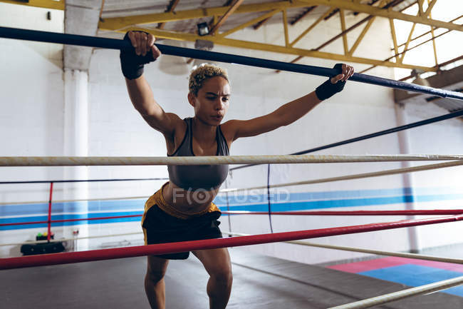 Вид спереду на жіночий боксерський кільце в боксерському клубі. Сильний жіночий боєць в тренажерному залі боксу важко . — стокове фото