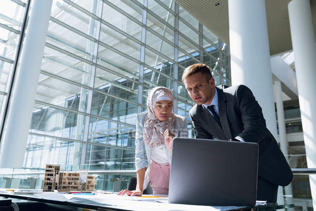 Multi-ethnic male and female architects discussing over laptop in office — Stock Photo