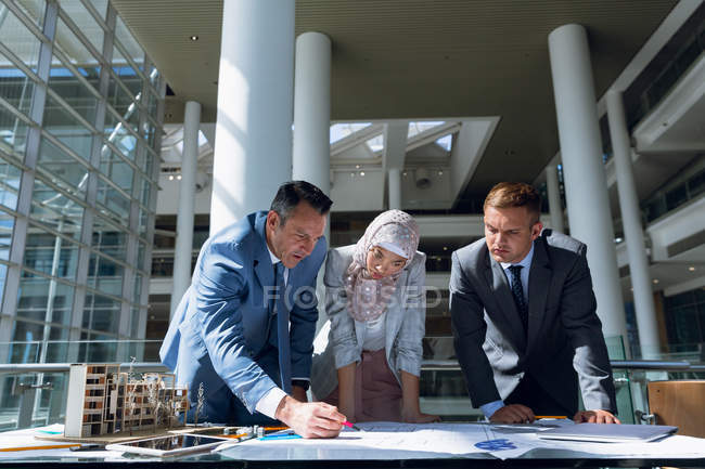 Multi-ethnic male and female architects discussing over blueprint in office. — Stock Photo