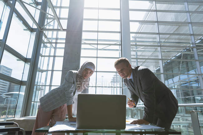 Multi-ethnic male and female architects discussing over laptop in office. — Stock Photo
